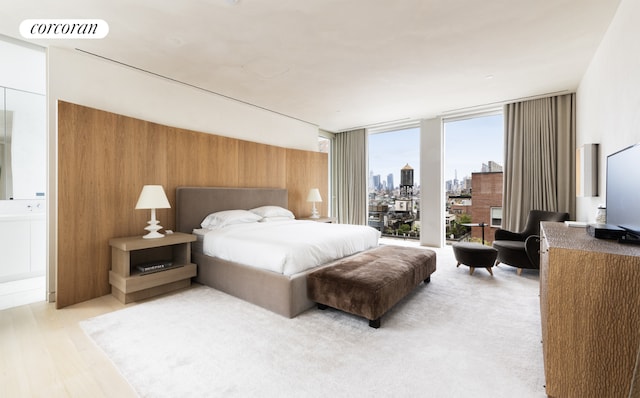 bedroom with expansive windows and light wood-type flooring