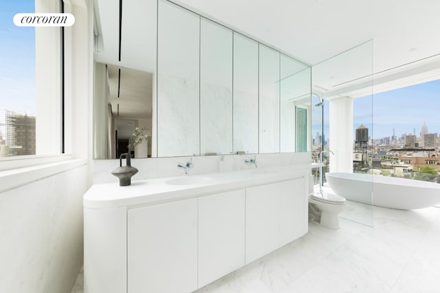 bathroom featuring vanity, a tub to relax in, a wall of windows, and toilet