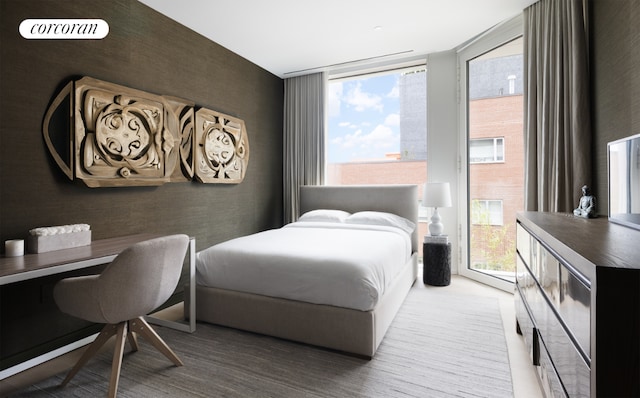 bedroom featuring expansive windows and hardwood / wood-style flooring