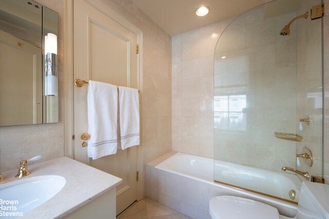 full bathroom featuring enclosed tub / shower combo, tile patterned floors, vanity, tile walls, and toilet