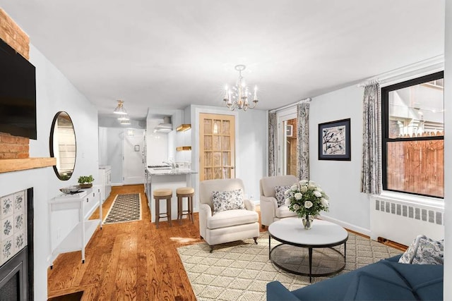 living room with light wood-type flooring, a notable chandelier, and radiator heating unit