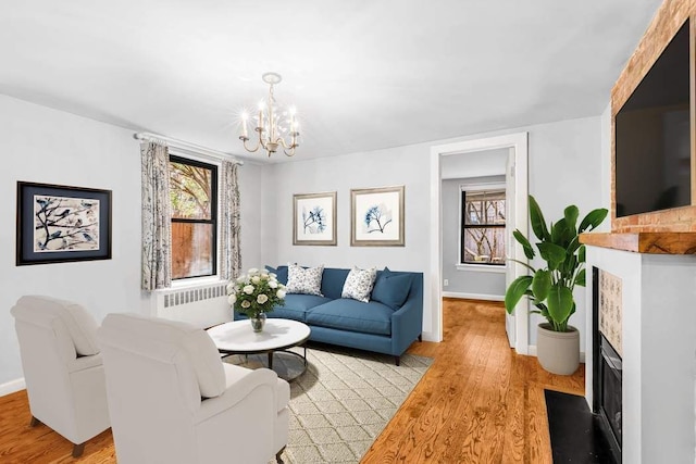 living room with radiator, light wood-type flooring, and an inviting chandelier