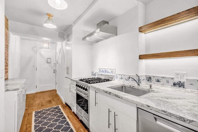 kitchen featuring white cabinetry, ventilation hood, stainless steel appliances, light wood-type flooring, and sink