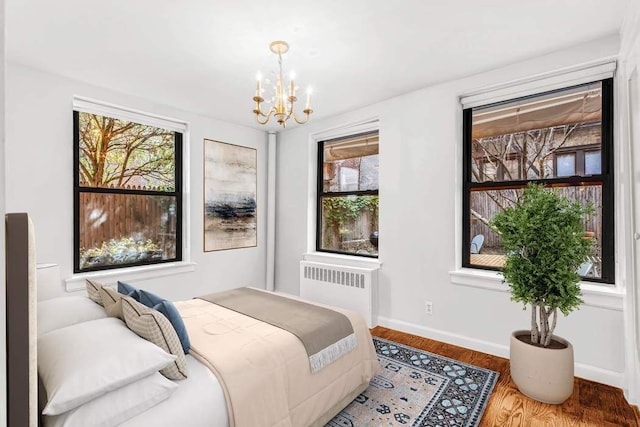 bedroom with hardwood / wood-style flooring, radiator, and an inviting chandelier