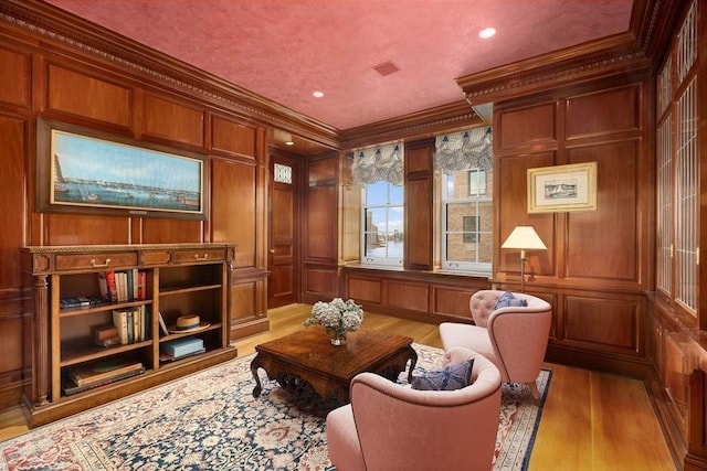 sitting room featuring crown molding, light hardwood / wood-style floors, and wood walls