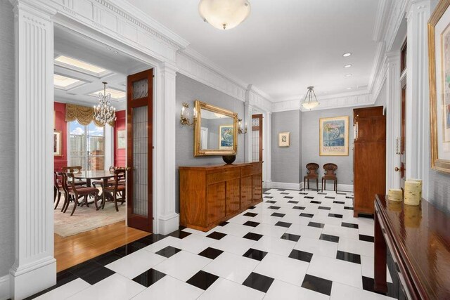 hallway featuring an inviting chandelier, ornamental molding, and ornate columns