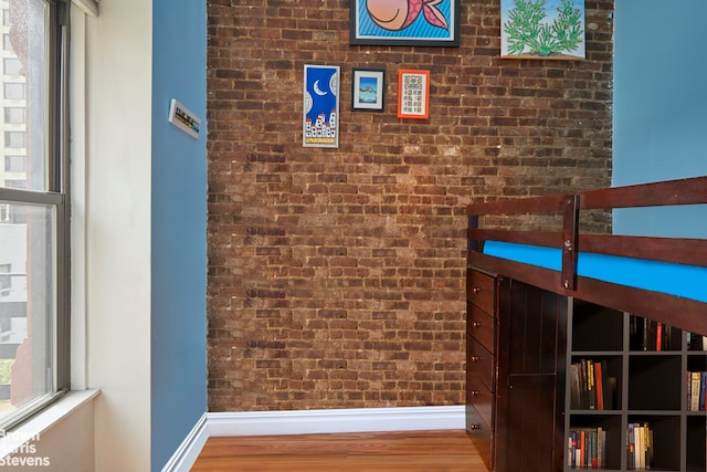 hall featuring brick wall and hardwood / wood-style floors