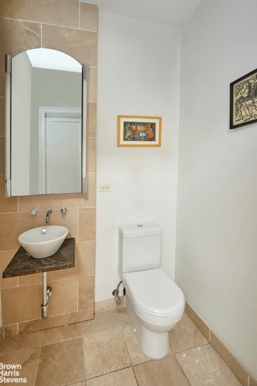 bathroom featuring toilet, sink, and decorative backsplash