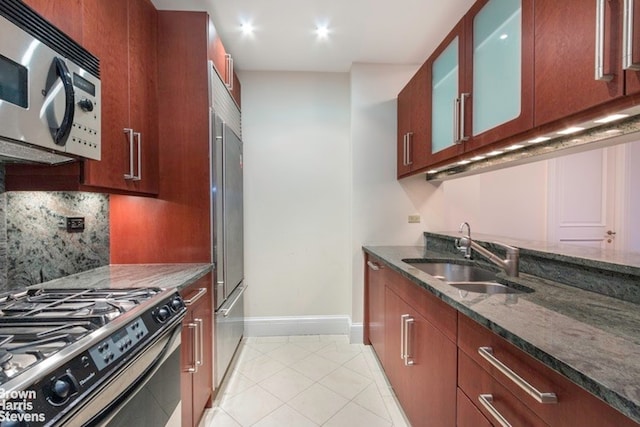 kitchen featuring dark stone countertops, decorative backsplash, sink, light tile patterned flooring, and stainless steel appliances