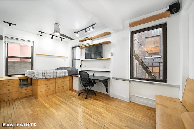 office area featuring ceiling fan, track lighting, built in desk, and light hardwood / wood-style floors