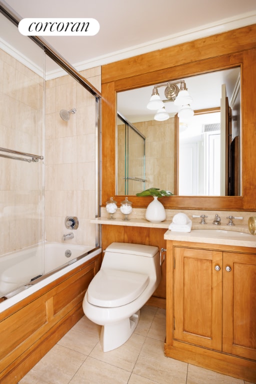 full bathroom with toilet, vanity, tile patterned flooring, crown molding, and shower / bath combination with glass door