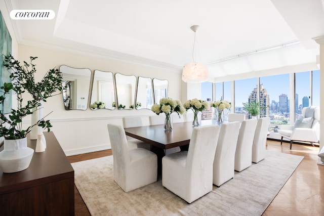 dining area with light wood-type flooring, a wealth of natural light, crown molding, and a chandelier