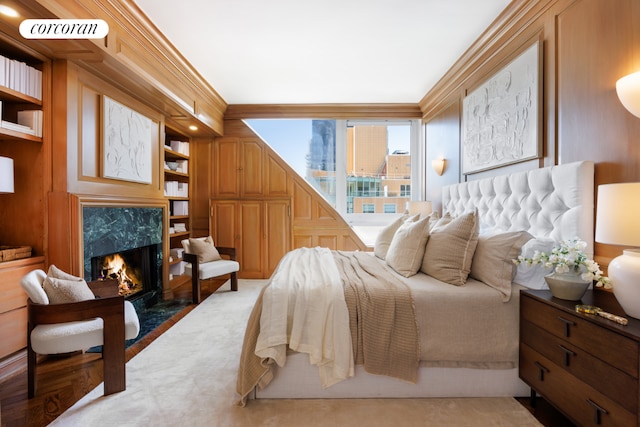 bedroom with a high end fireplace, crown molding, and wood walls