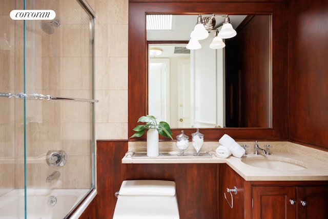 full bathroom featuring toilet, bath / shower combo with glass door, and vanity