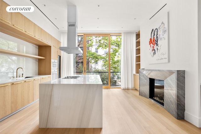 248 W 71st St, New York City, NY 10023 - kitchen featuring light brown cabinetry, modern cabinets, a sink, light wood-style floors, and expansive windows