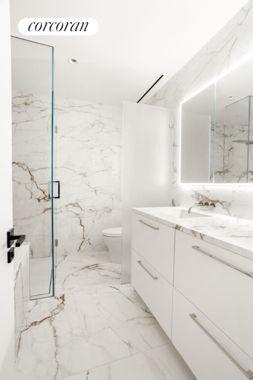 bathroom featuring toilet, vanity, and a shower with shower door