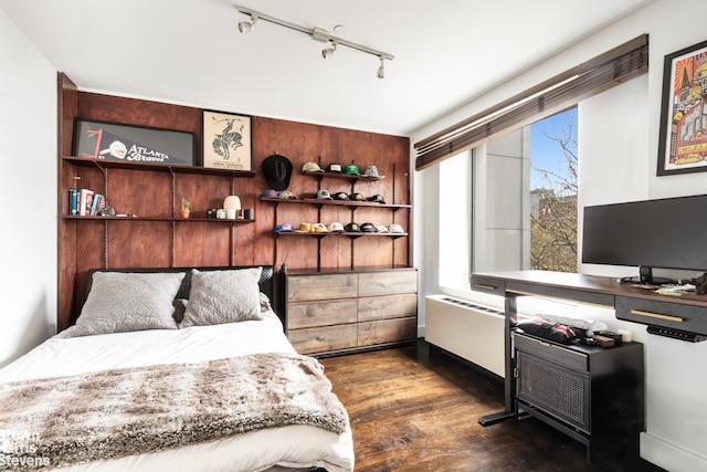 bedroom featuring dark wood-style floors, radiator heating unit, and rail lighting