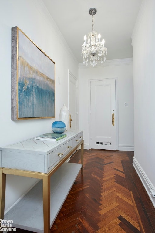 hallway featuring dark parquet flooring, ornamental molding, and an inviting chandelier