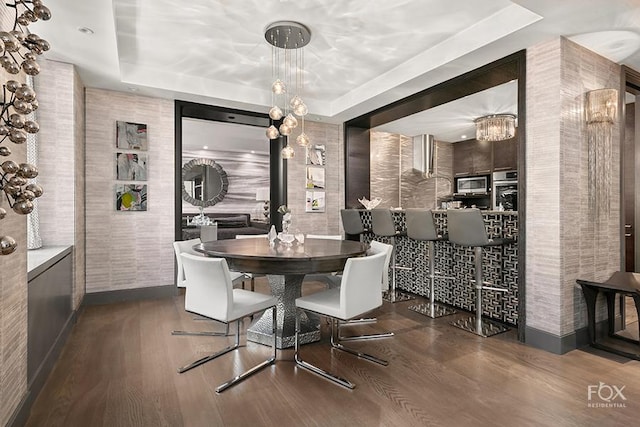 dining space with a tray ceiling and dark hardwood / wood-style flooring