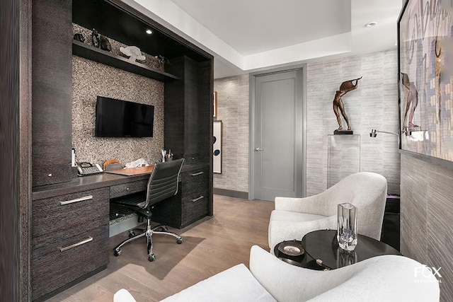 home office featuring a raised ceiling and light hardwood / wood-style flooring