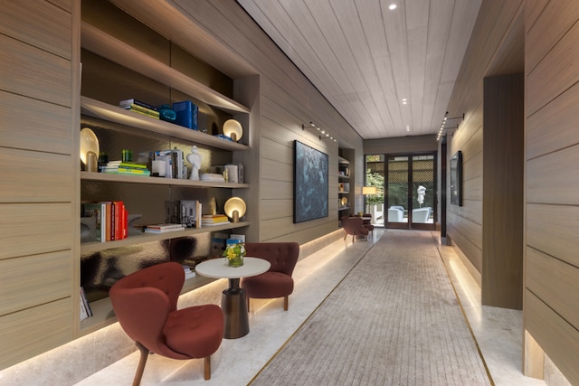 corridor featuring wood walls, finished concrete floors, built in shelves, and recessed lighting