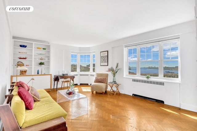 living room with radiator, parquet floors, and a healthy amount of sunlight