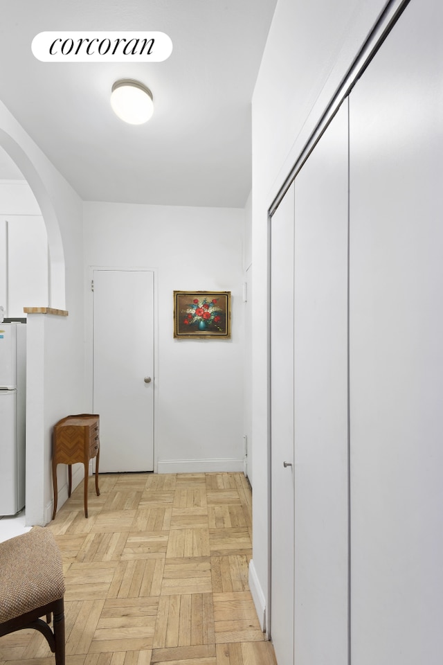 hallway featuring baseboards and arched walkways