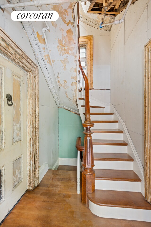 stairs featuring hardwood / wood-style flooring and lofted ceiling