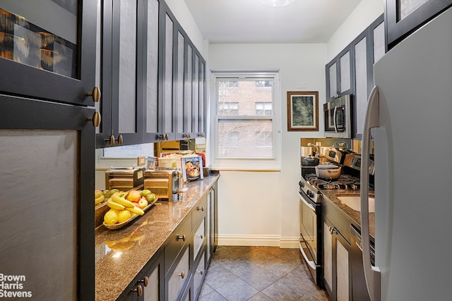 kitchen featuring stainless steel appliances, dark tile patterned flooring, and light stone countertops