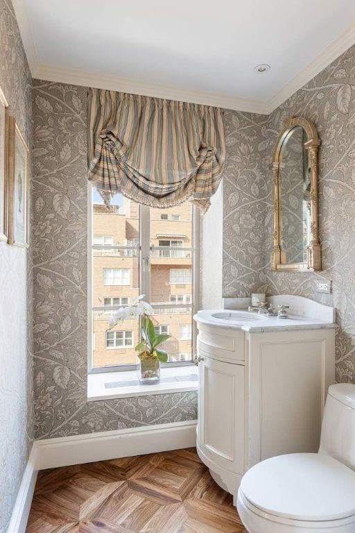 bathroom featuring vanity, crown molding, parquet flooring, and toilet