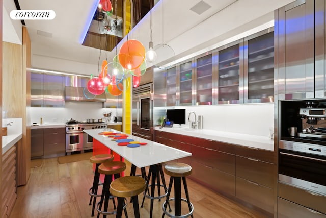 kitchen with light wood-type flooring, a kitchen breakfast bar, high quality appliances, and pendant lighting