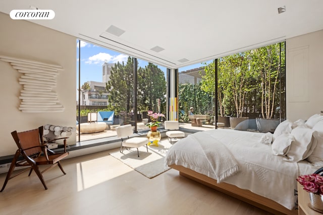 bedroom with multiple windows, expansive windows, and hardwood / wood-style floors