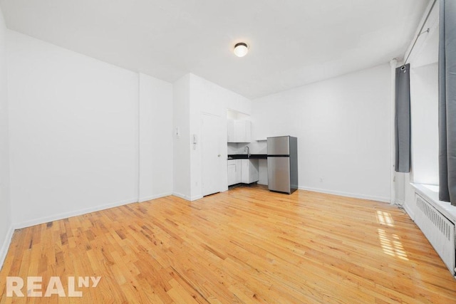 spare room featuring radiator and light hardwood / wood-style floors