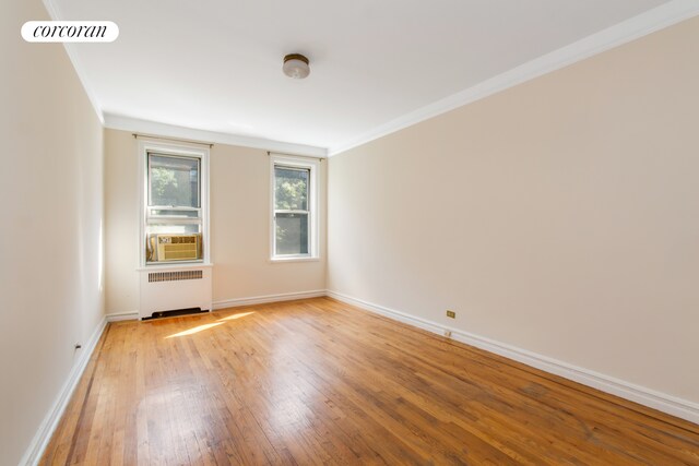 empty room with crown molding, built in features, radiator heating unit, and dark parquet floors