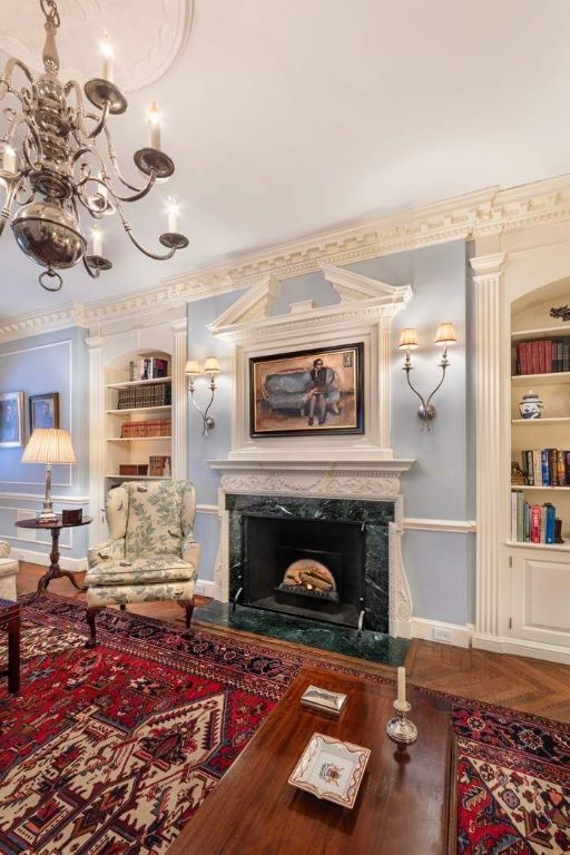 living area with a notable chandelier, ornamental molding, built in features, and a high end fireplace