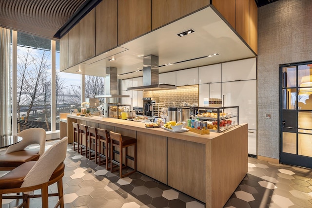 kitchen featuring a towering ceiling, island range hood, and ventilation hood