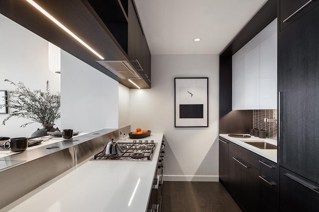 kitchen with dark wood finished floors, tasteful backsplash, light countertops, stainless steel gas stovetop, and modern cabinets