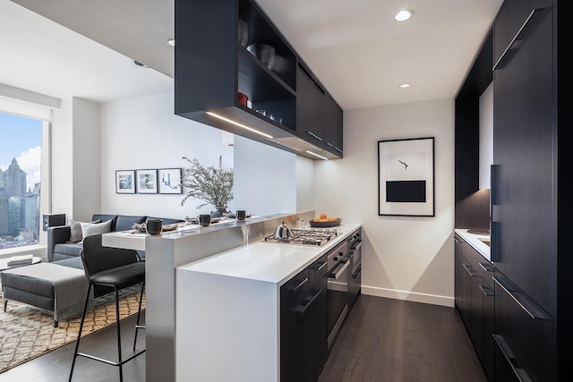 kitchen featuring dark wood finished floors, light countertops, modern cabinets, a peninsula, and a kitchen bar