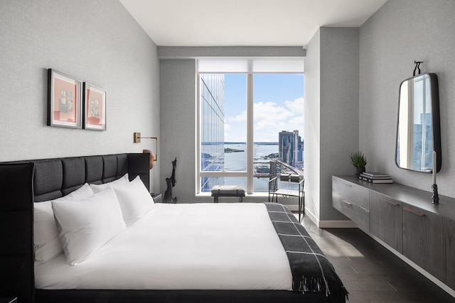 bedroom featuring dark wood-style floors, floor to ceiling windows, and baseboards