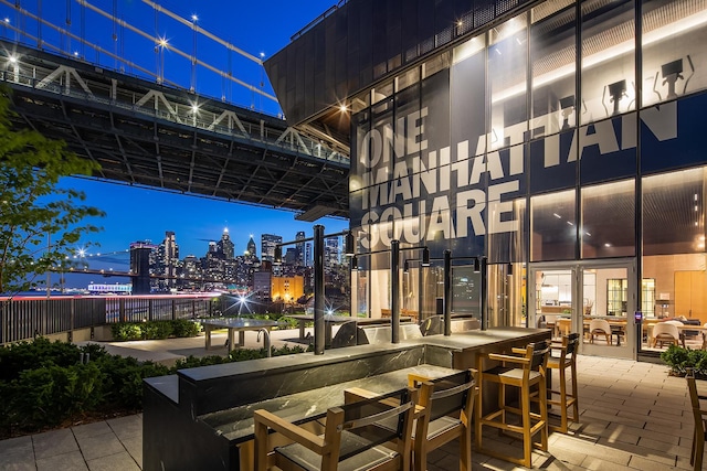 view of patio featuring a view of city lights and outdoor dry bar