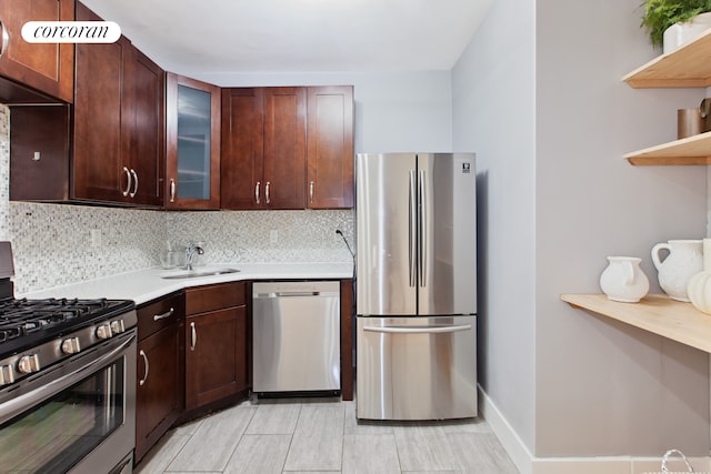 kitchen featuring decorative backsplash, glass insert cabinets, stainless steel appliances, light countertops, and a sink