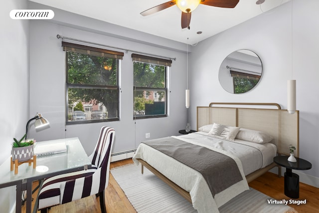 bedroom featuring a baseboard heating unit, hardwood / wood-style flooring, and ceiling fan