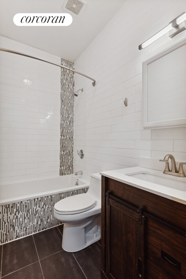 full bathroom featuring tiled shower / bath, tile walls, vanity, and toilet