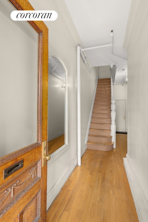 staircase featuring wood-type flooring and ornamental molding