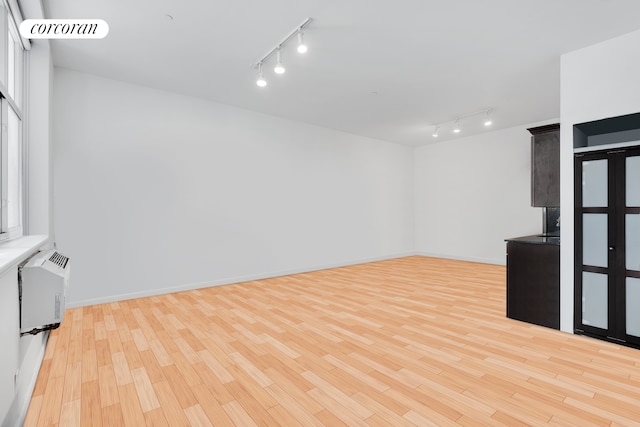 unfurnished living room featuring a wall mounted AC, light wood-style floors, visible vents, and baseboards