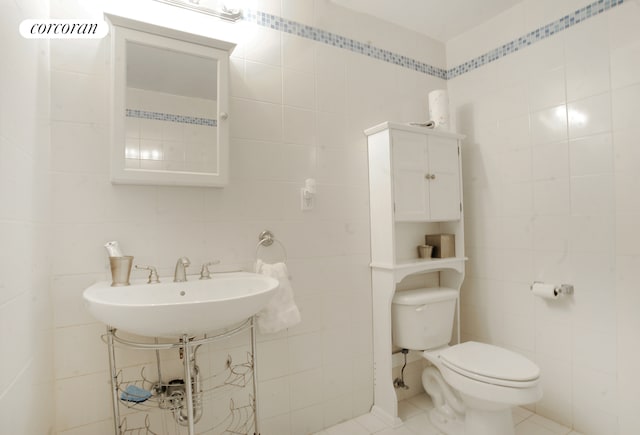 bathroom with a sink, toilet, tile walls, and tile patterned floors