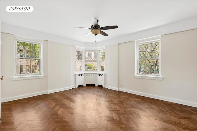 spare room with radiator, dark parquet floors, and ceiling fan