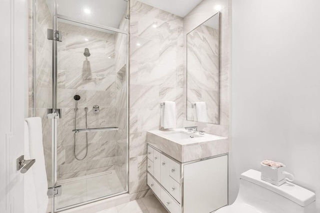 bathroom with vanity, toilet, a shower with door, and tile walls