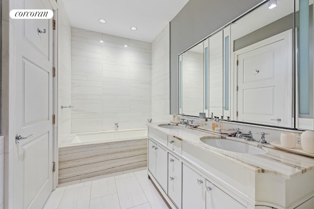 bathroom featuring a relaxing tiled tub and vanity