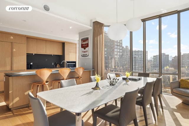 dining area with a wall of windows and light hardwood / wood-style floors